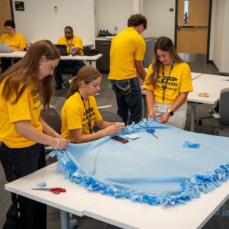Interns working together on a fleece blanket 